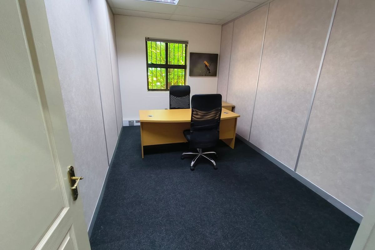 A functional office space featuring carpeted flooring, partition walls, and a recessed ceiling light, providing a professional environment for work.