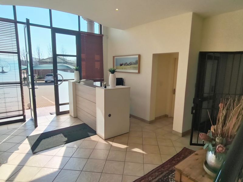 Bright and welcoming office entrance featuring large glass windows, tiled flooring, and a built-in reception desk.