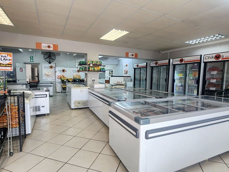 A well-maintained retail space featuring a suspended ceiling, tiled flooring, and multiple commercial refrigeration units for food display.