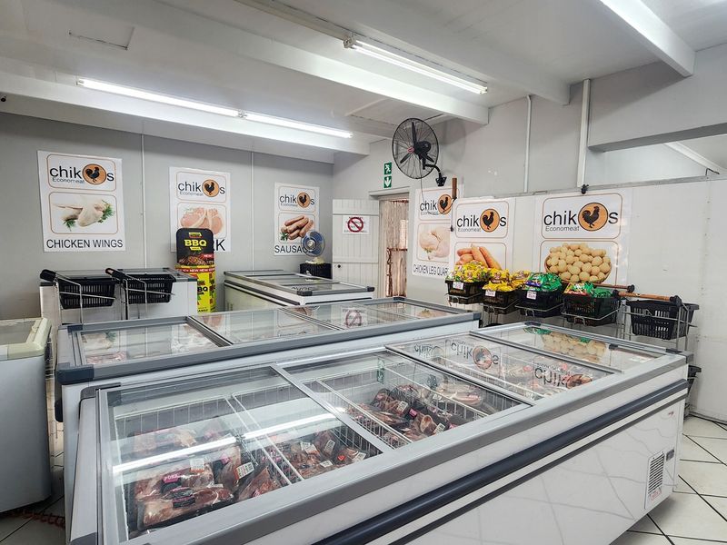 A retail meat shop interior featuring multiple commercial chest freezers, tiled flooring, and overhead fluorescent lighting.