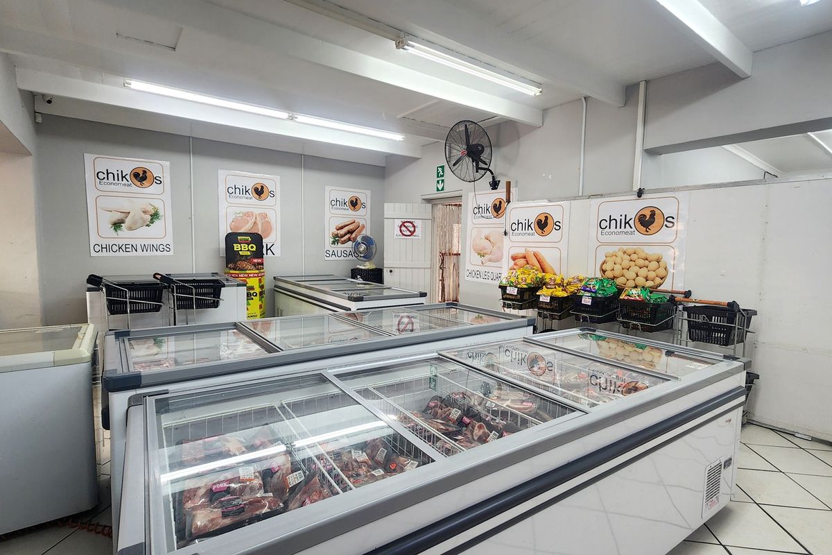 A retail meat shop interior featuring multiple commercial chest freezers, tiled flooring, and overhead fluorescent lighting.