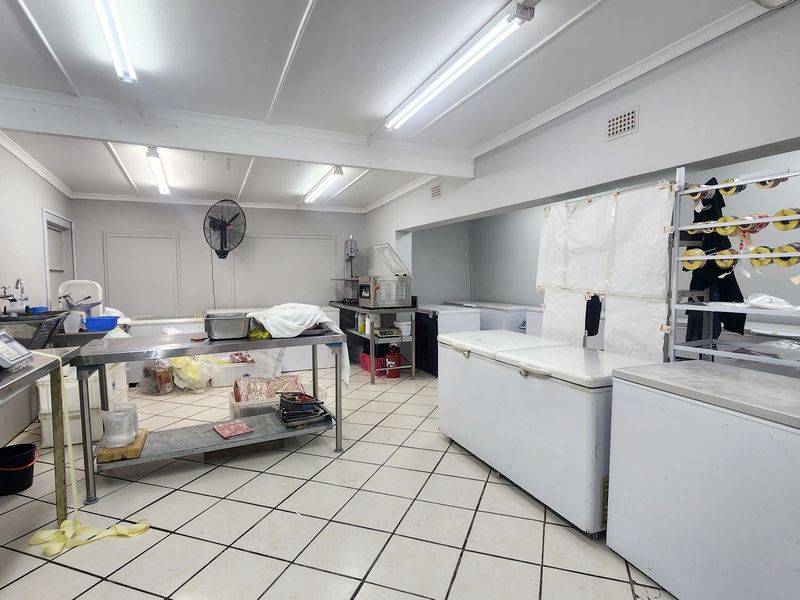 A functional commercial utility or food preparation space featuring tiled flooring, stainless steel work surfaces, and integrated storage shelving.