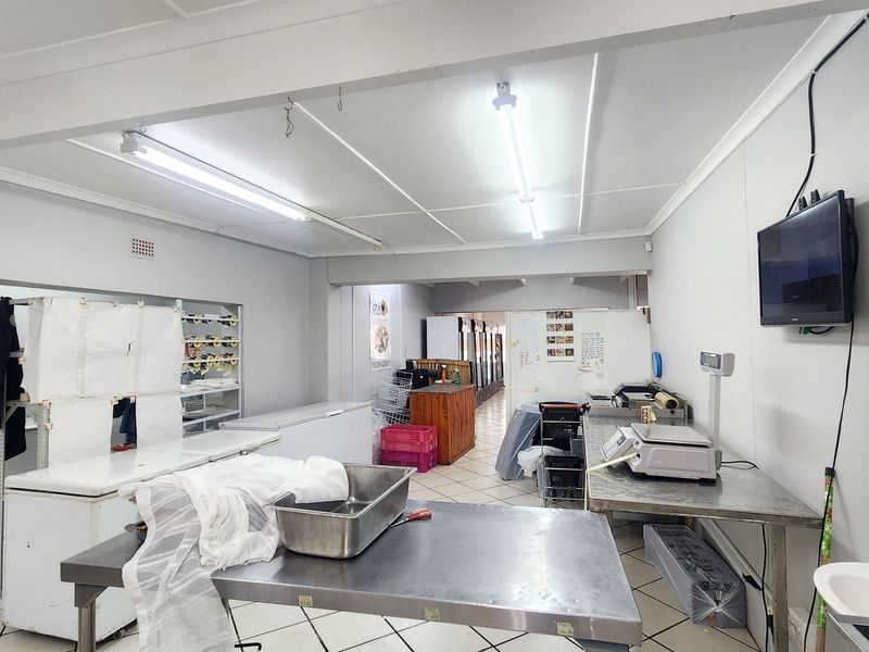 Commercial kitchen space featuring stainless steel prep tables, tiled flooring, and functional utility fixtures suitable for food preparation and retail operations.
