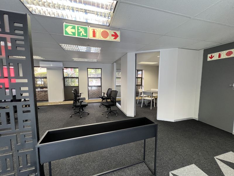 A professional office space featuring carpeted flooring, suspended ceilings with recessed lighting, glass partitions, and integrated air conditioning, providing a functional work environment.