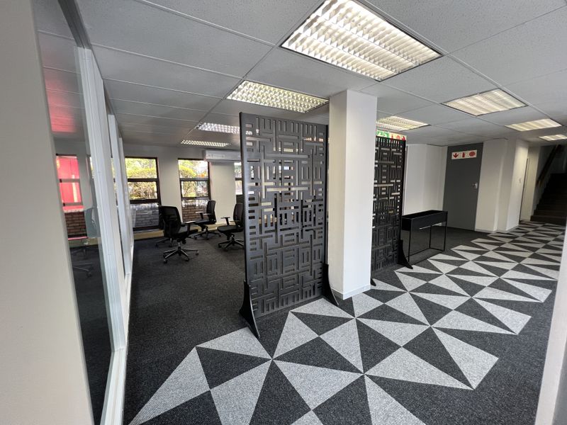Modern office space featuring suspended ceilings, recessed lighting, patterned carpet tiles, and glass partitioning, providing a professional and functional work environment.