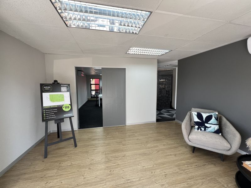 A bright and modern office reception area featuring laminate flooring, recessed lighting, and a neutral color palette with a feature wall.