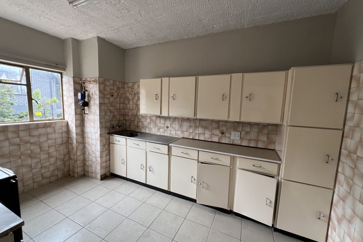 A dated kitchen featuring original cabinetry, tiled splashbacks, and tiled flooring, offering a blank canvas for a modern renovation.