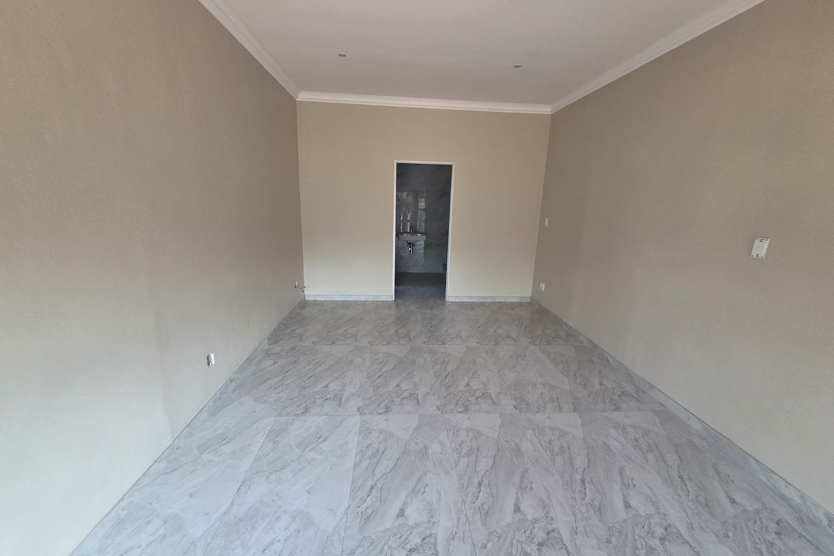 A spacious, empty open-plan retail area featuring modern marble-effect floor tiles, neutral wall finishes, and recessed ceiling lighting with coved cornicing.