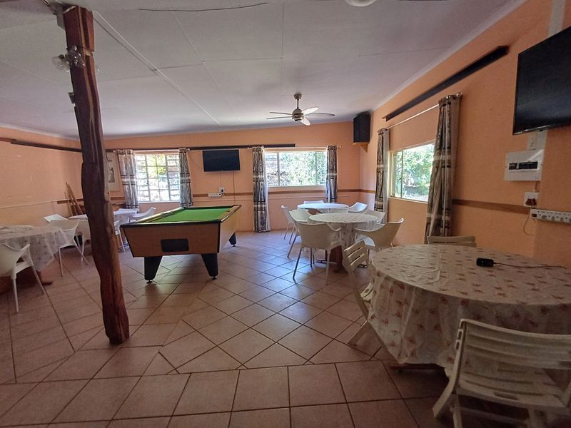 Spacious lodge living area featuring tiled flooring, a central ceiling fan, and a rustic exposed timber support post.