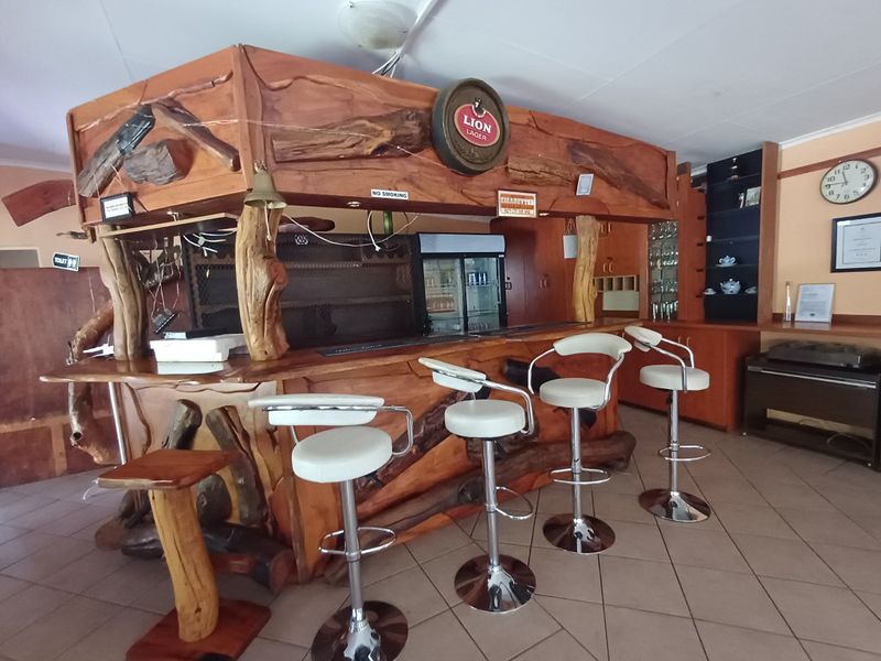 A rustic-style lodge bar featuring a custom timber counter, integrated beverage cooling, and tiled flooring, providing a dedicated space for entertainment and social gatherings.