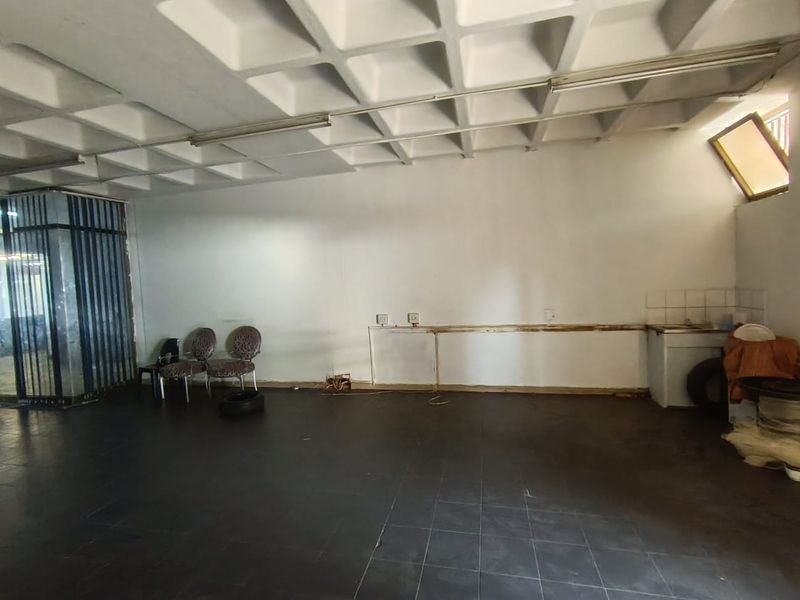 Open plan retail space featuring a coffered ceiling, dark tiled flooring, and a small built-in kitchenette area.