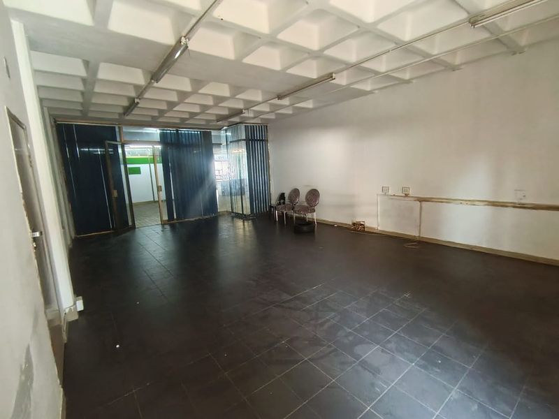 Open plan retail or office space featuring dark tiled flooring, a coffered ceiling design, and glass partition doors.