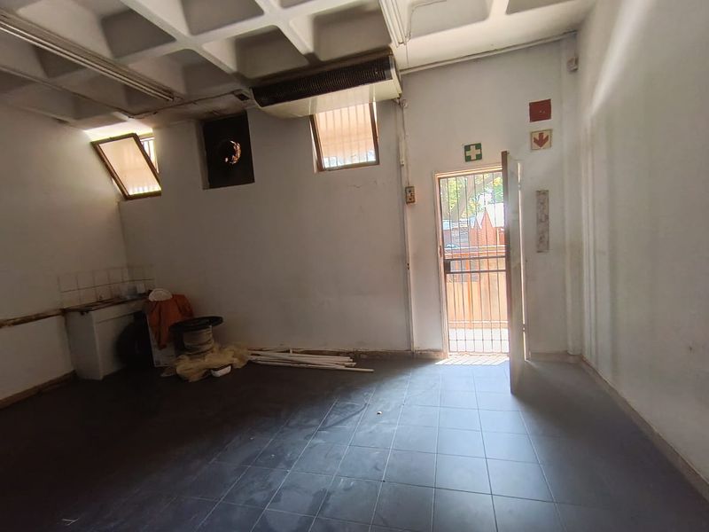 Utility space featuring a coffered ceiling, tiled flooring, and direct exterior access, suitable for storage or back-of-house operations.