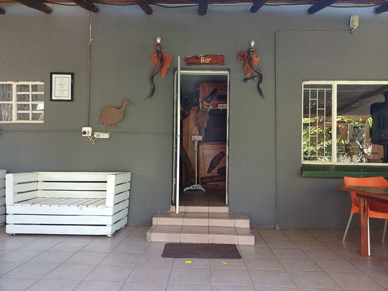 Covered patio area featuring tiled flooring, exposed timber beams, and direct access to the bar area, providing a functional outdoor entertainment space.
