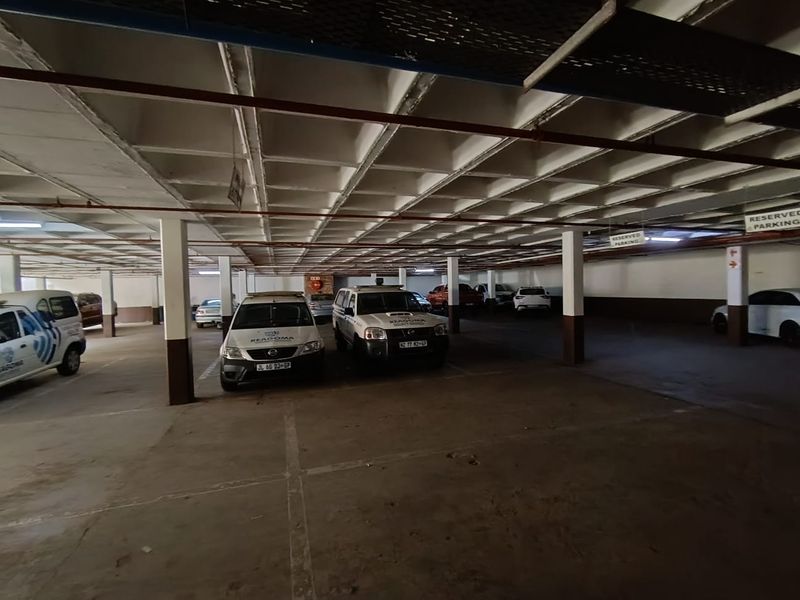 Covered basement parking area with concrete flooring, structural support columns, and overhead grid ceiling system.
