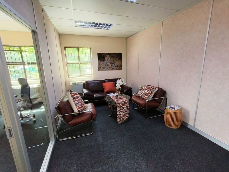 A professional office space featuring carpeted flooring, suspended ceilings with recessed lighting, and a glass partition wall, providing a functional work environment.