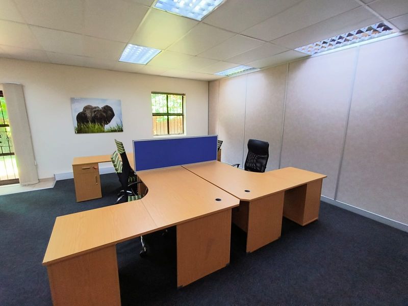 A functional office space featuring modular partition walling, suspended ceiling with recessed lighting, and carpeted flooring, suitable for a professional work environment.