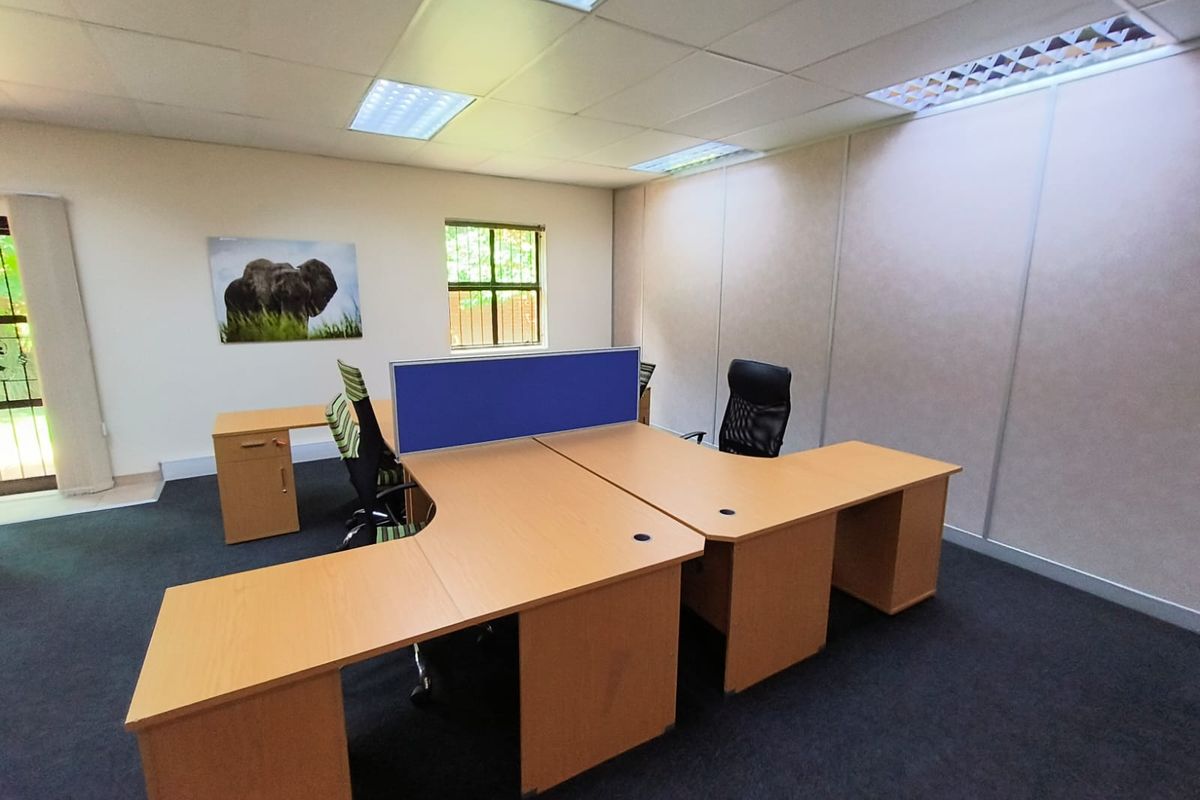 A functional office space featuring modular partition walling, suspended ceiling with recessed lighting, and carpeted flooring, suitable for a professional work environment.