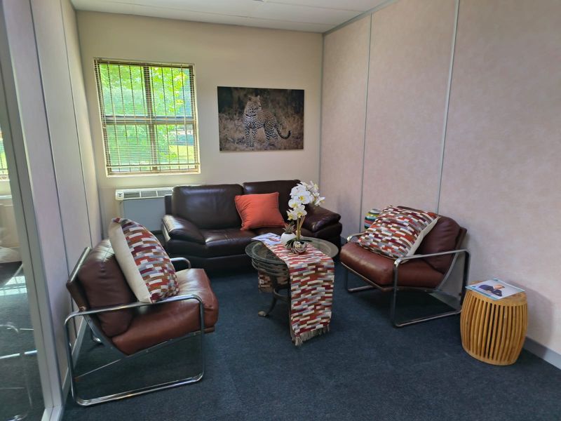 A compact office space featuring carpeted flooring, partitioned wall panels, and a wall-mounted air conditioning unit.