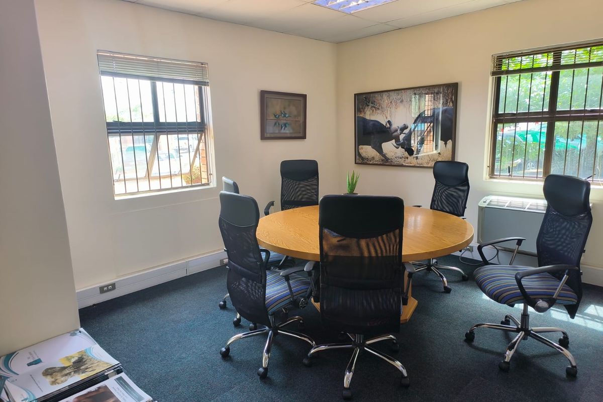 A functional office space featuring carpeted flooring, recessed lighting, security bars on windows, and a built-in air conditioning unit.