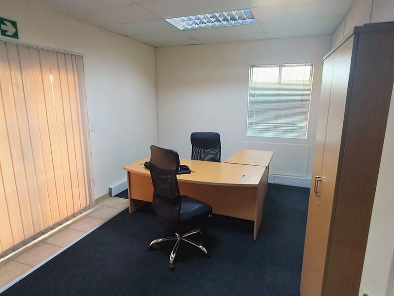 A functional office space featuring carpeted flooring, suspended ceilings with recessed lighting, and window blinds for privacy and light control.
