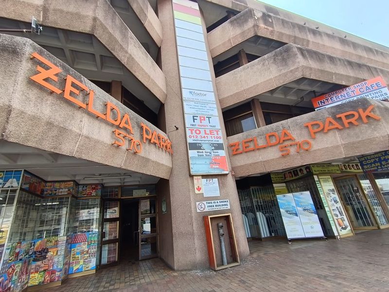 Exterior view of Zelda Park office building featuring a multi-level concrete facade with ground-floor retail and office entrance access.