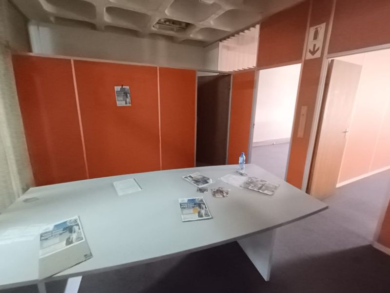 A functional office space featuring modular partition walls, a built-in desk, and a suspended waffle ceiling design.