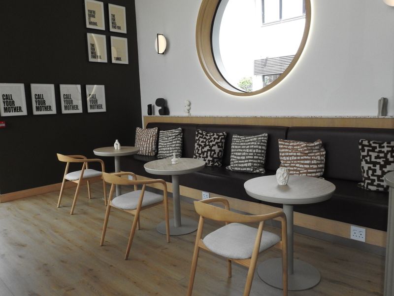 Modern office breakout area featuring built-in bench seating, a distinctive circular window, and contemporary laminate flooring.