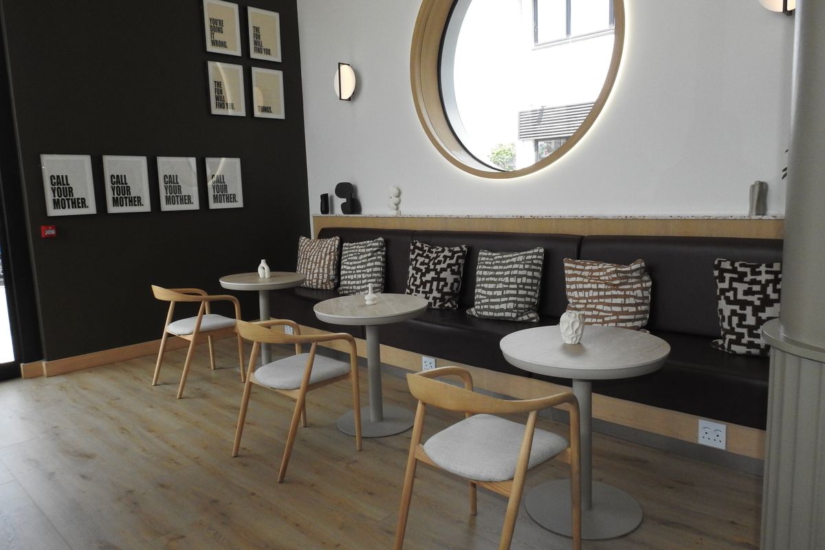 Modern office breakout area featuring built-in bench seating, a distinctive circular window, and contemporary laminate flooring.
