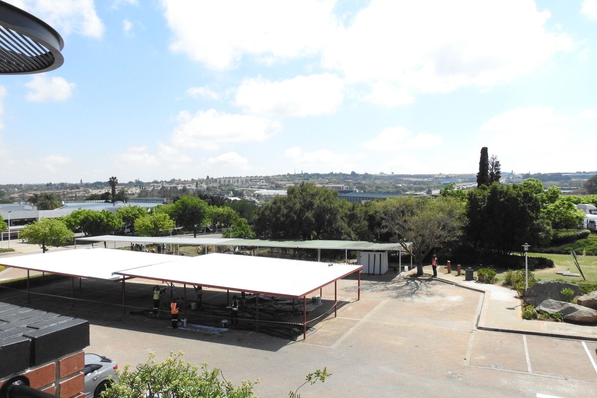 An elevated view of the office property exterior, featuring a paved parking area with covered bays and surrounding landscaped grounds.