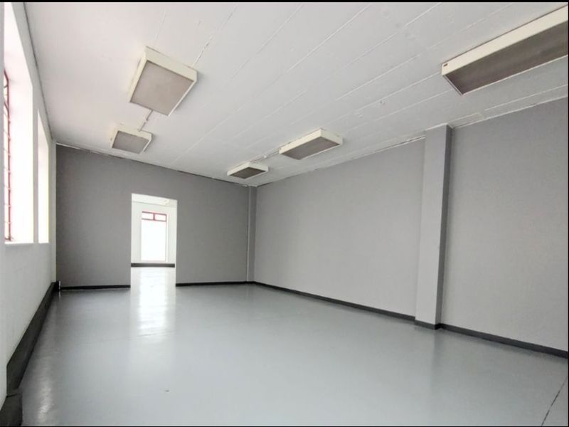 A clean, open-plan industrial utility space featuring durable epoxy flooring, neutral grey walls, and functional overhead fluorescent lighting.