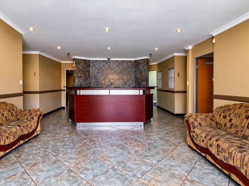 Professional office reception area featuring a built-in reception desk, tiled flooring, and recessed lighting, providing a functional welcome space for clients.