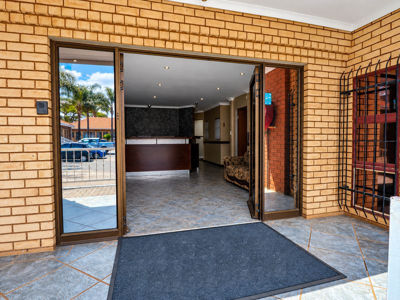 Entrance area featuring a brick facade, sliding glass doors, and a view into the reception area with tiled flooring and recessed lighting.