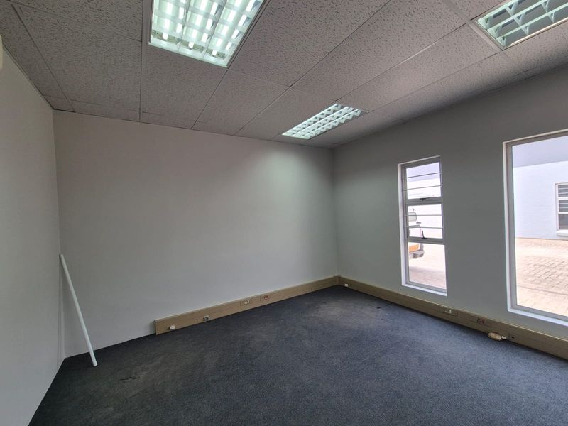 A vacant office space featuring a suspended ceiling with recessed lighting, carpeted flooring, and perimeter trunking for electrical connectivity.