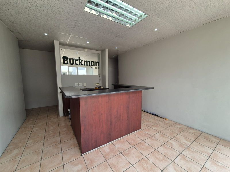 A professional office reception area featuring a built-in service counter, tiled flooring, and a drop ceiling with integrated lighting.