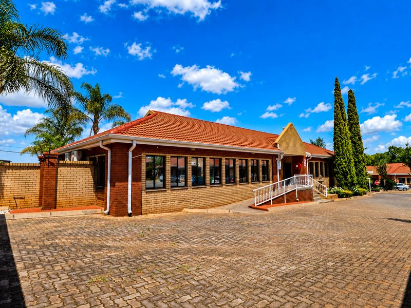 Front exterior view of a brick office building featuring a tiled roof, paved driveway, and an accessibility ramp at the entrance.