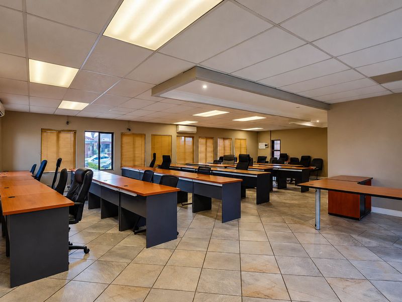 Spacious office area featuring tiled flooring, suspended ceilings with recessed lighting, and multiple windows with fitted venetian blinds.
