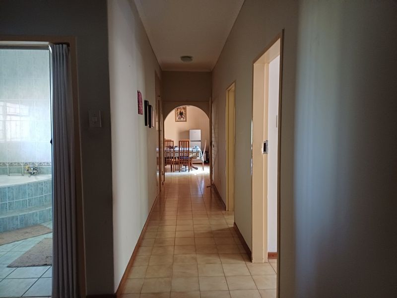 A central hallway with tiled flooring and an arched transition leading into the living area, providing access to adjacent rooms.