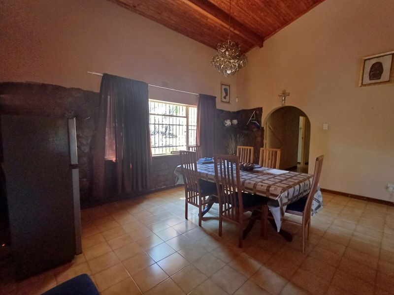 Dining room featuring a high exposed timber ceiling, stone accent wall, and ceramic tiled flooring with an arched entryway.