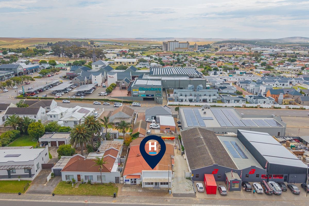 Aerial view of a commercial property featuring a metal roof, adjacent to a retail shopping center and surrounding urban infrastructure.
