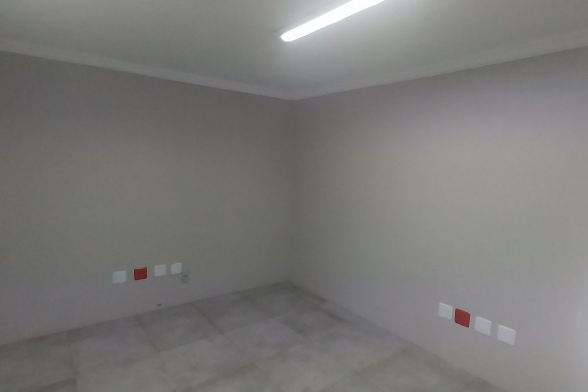 A clean, empty office space featuring neutral wall finishes, tiled flooring, and integrated electrical and data connectivity points.