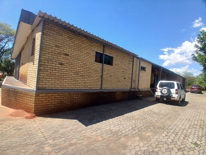 Exterior view of an industrial building featuring face brick construction, a corrugated metal roof, and a paved driveway area.