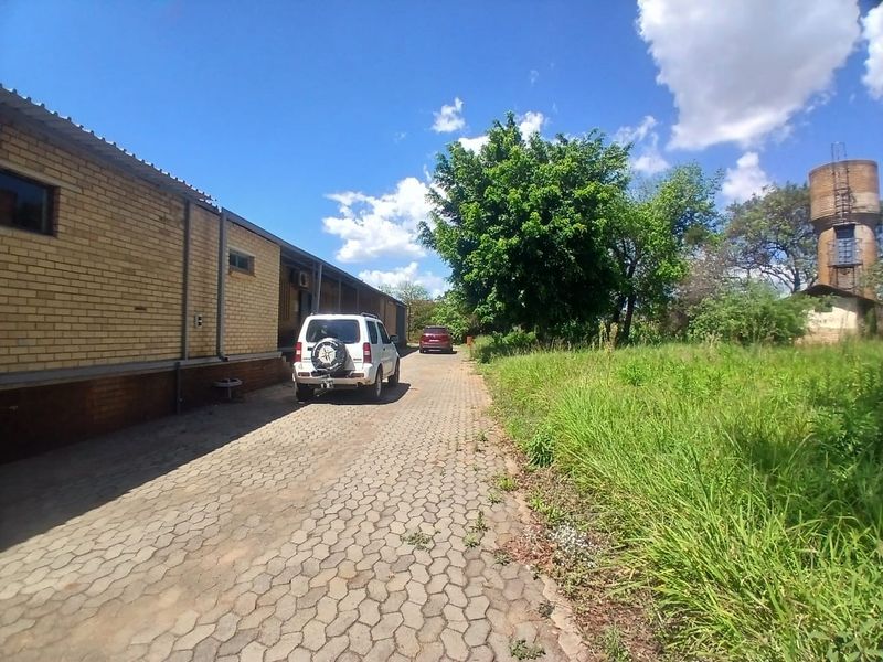 Exterior view of an industrial property featuring a brick facade, paved driveway, and an adjacent water tower on the premises.