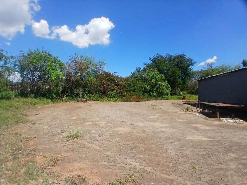 Spacious industrial yard area featuring paved ground, perimeter fencing, and an adjacent metal structure, suitable for storage or operational use.