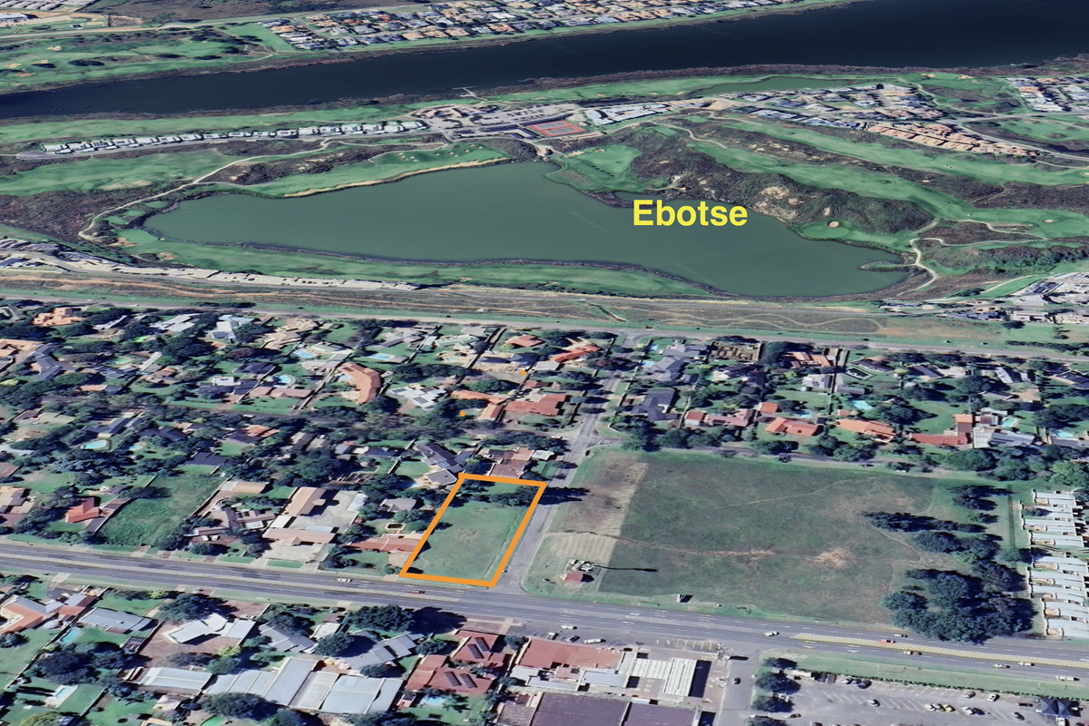 Aerial view of a vacant commercial land plot highlighted in orange, situated in a developed residential and commercial area near Ebotse.