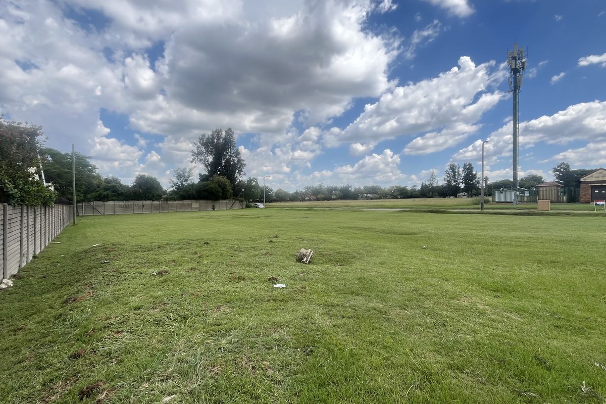 A wide, level vacant commercial plot featuring perimeter concrete walling and clear access, suitable for development.
