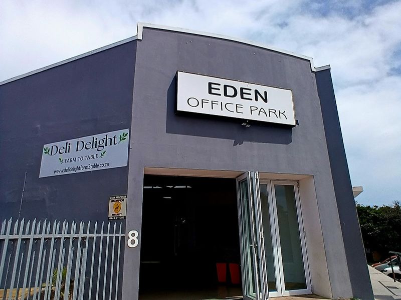 Front entrance view of Eden Office Park featuring a paved approach, security fencing, and modern bi-fold glass doors.