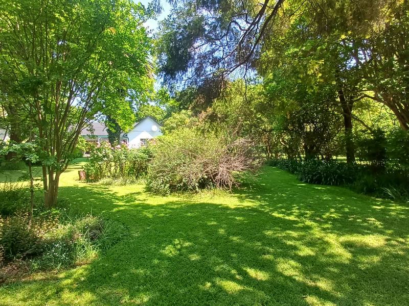 A lush, well-established garden featuring mature trees and expansive green lawns, providing a serene outdoor setting on the farm property.