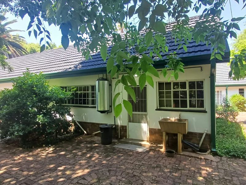 Rear exterior view of the farm property featuring a tiled roof, brick paved courtyard, and an external wash basin area.