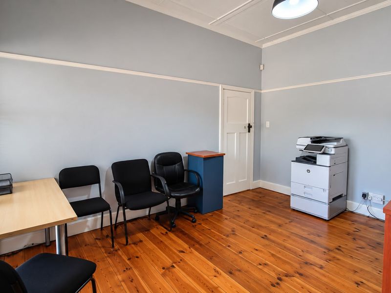 A functional office space featuring polished timber flooring, classic picture rails, and a panelled door, providing a professional and well-maintained work environment.